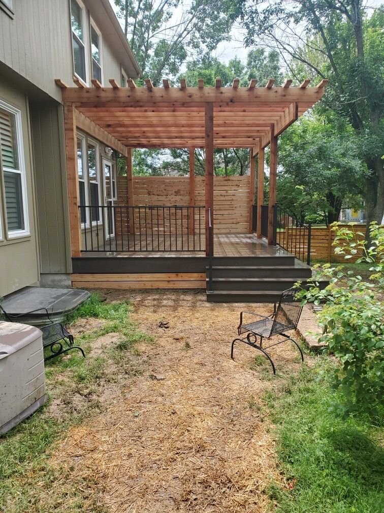 A wooden deck with a pergola and stairs in the backyard of a house.