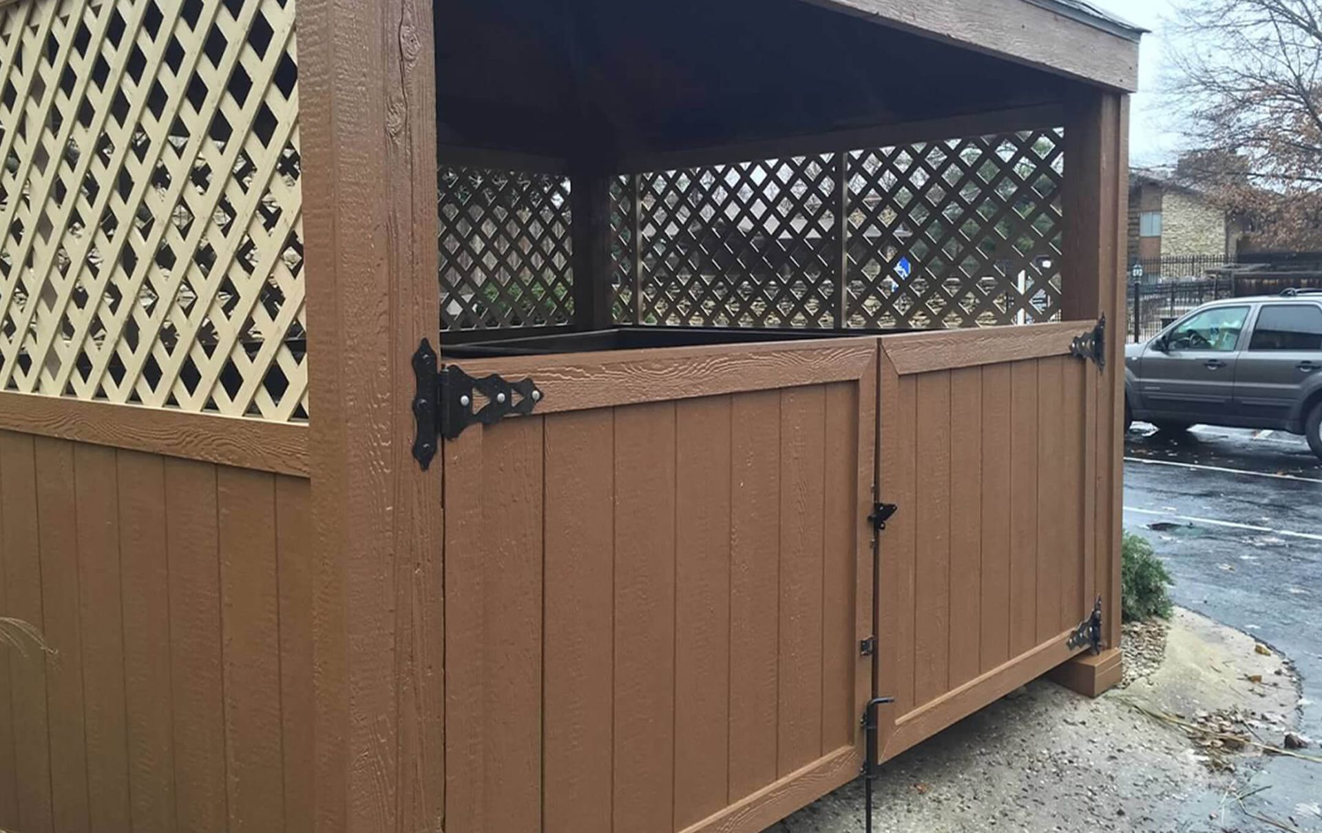 A brown wooden shed with a lattice fence and a gate.