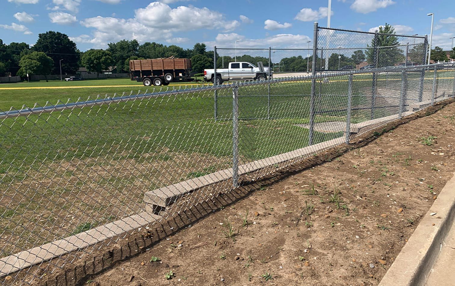 A chain link fence surrounds a baseball field.