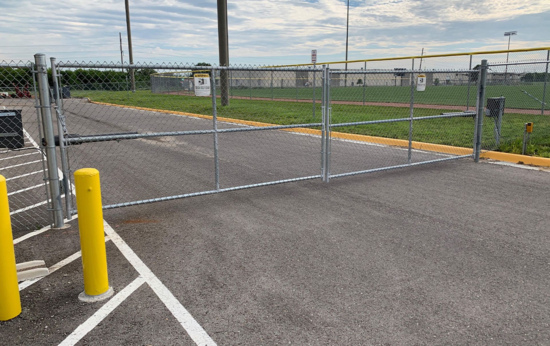 A chain link fence is sitting in the middle of a parking lot.