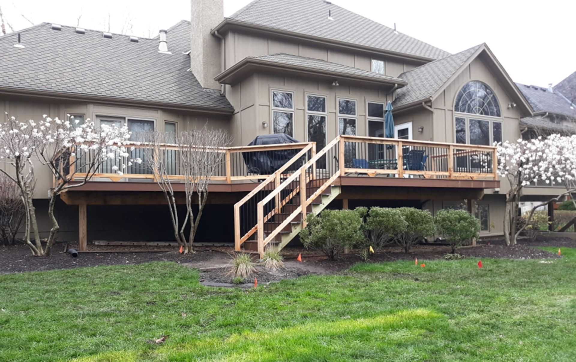A large house with a wooden deck and stairs in front of it.