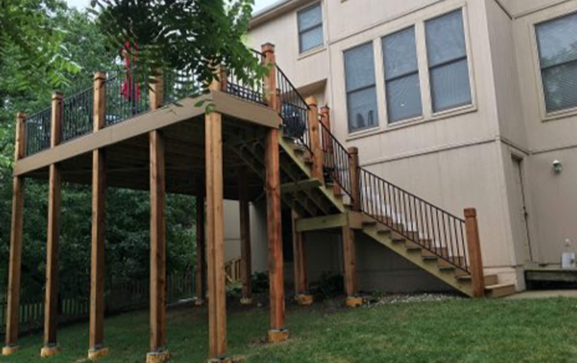 A large house with a wooden deck and stairs leading up to it.