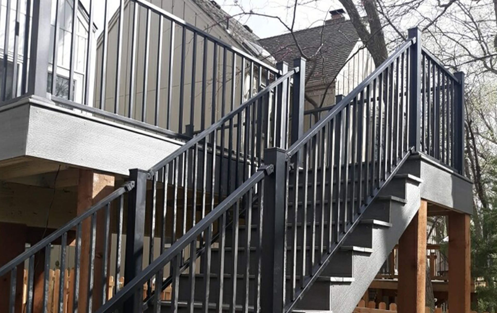 A set of stairs leading up to a deck with a black railing.