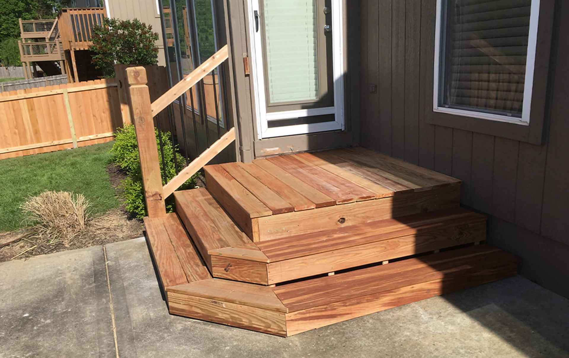 A wooden deck with stairs leading up to the door of a house.