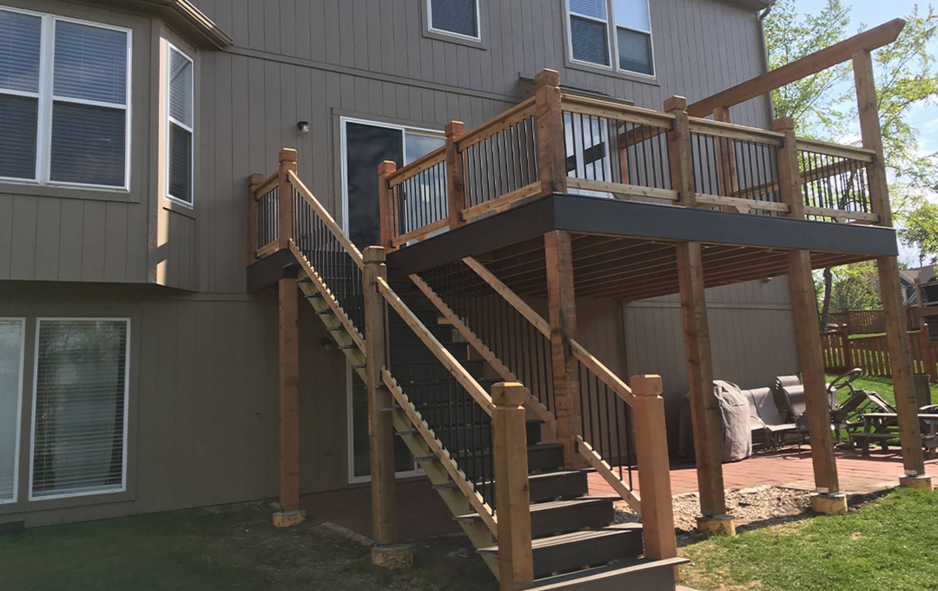 A wooden deck with stairs leading up to it is in front of a house.