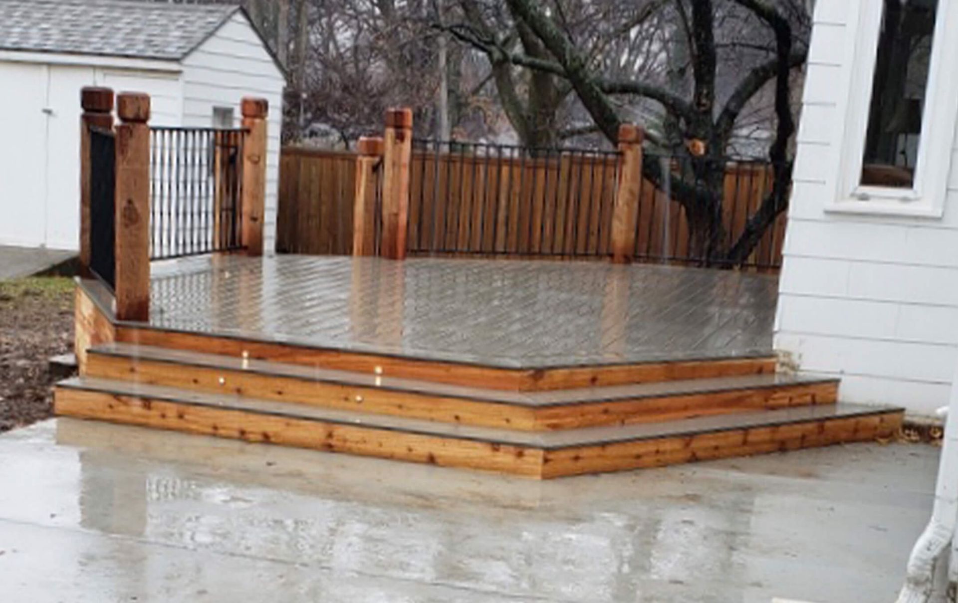 A white house with a wooden deck and stairs in front of it.