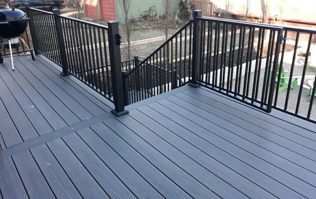 A composite deck with a black railing and stairs.