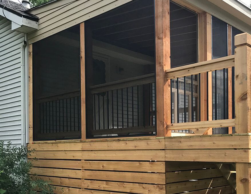A screened in porch with a white house in the background