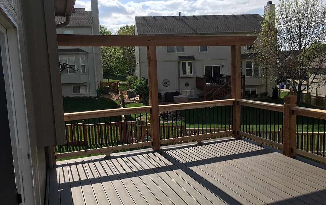 A wooden deck with a railing and a house in the background.