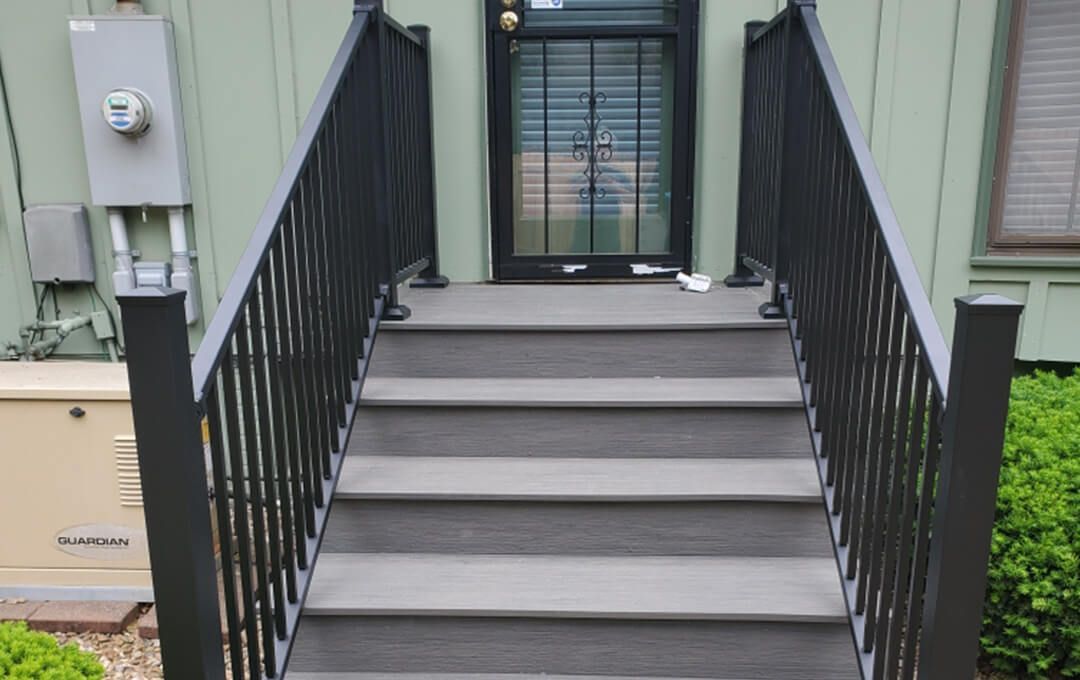 A set of stairs leading up to a house with a black railing.