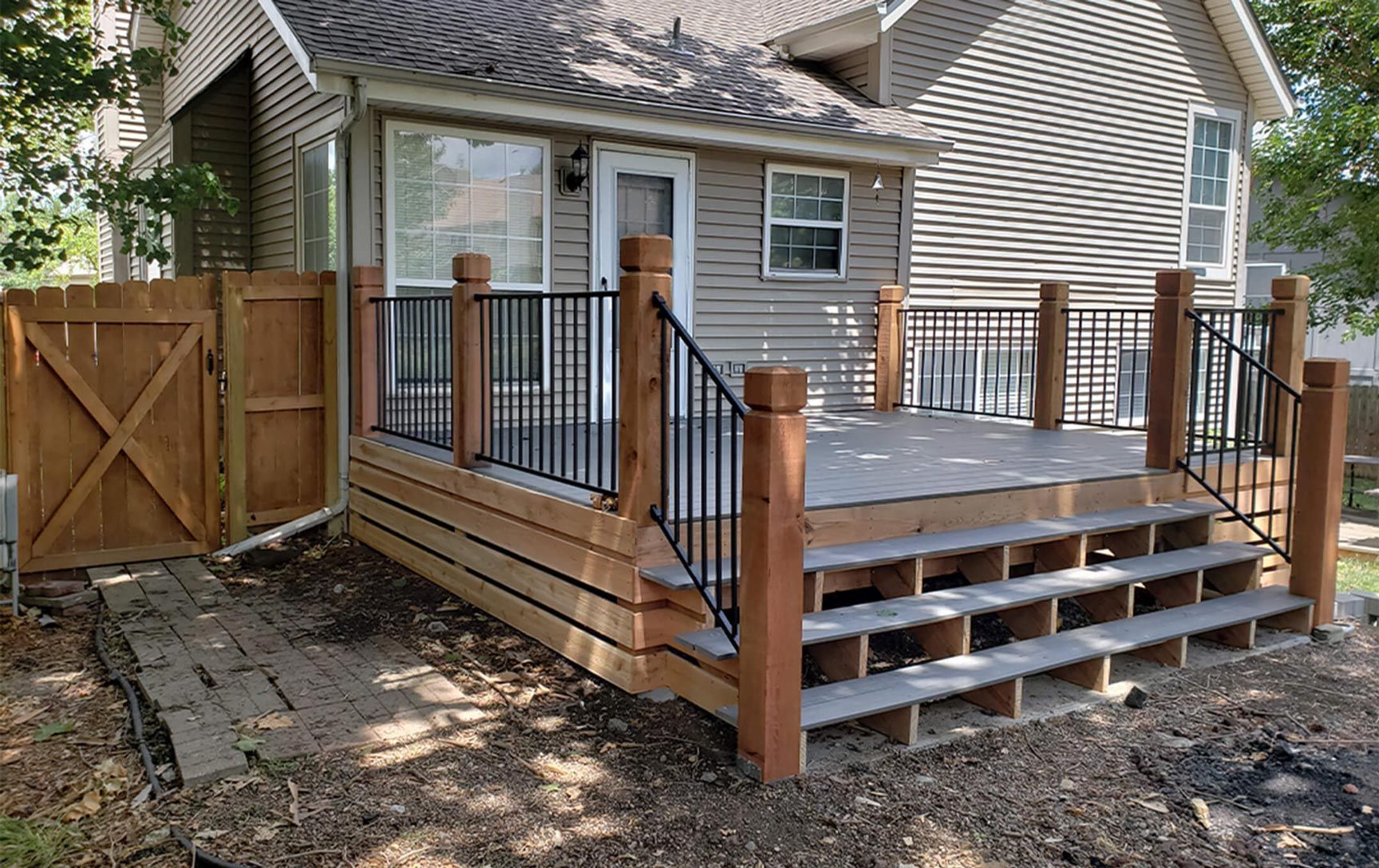 A house with a wooden deck and stairs in front of it.