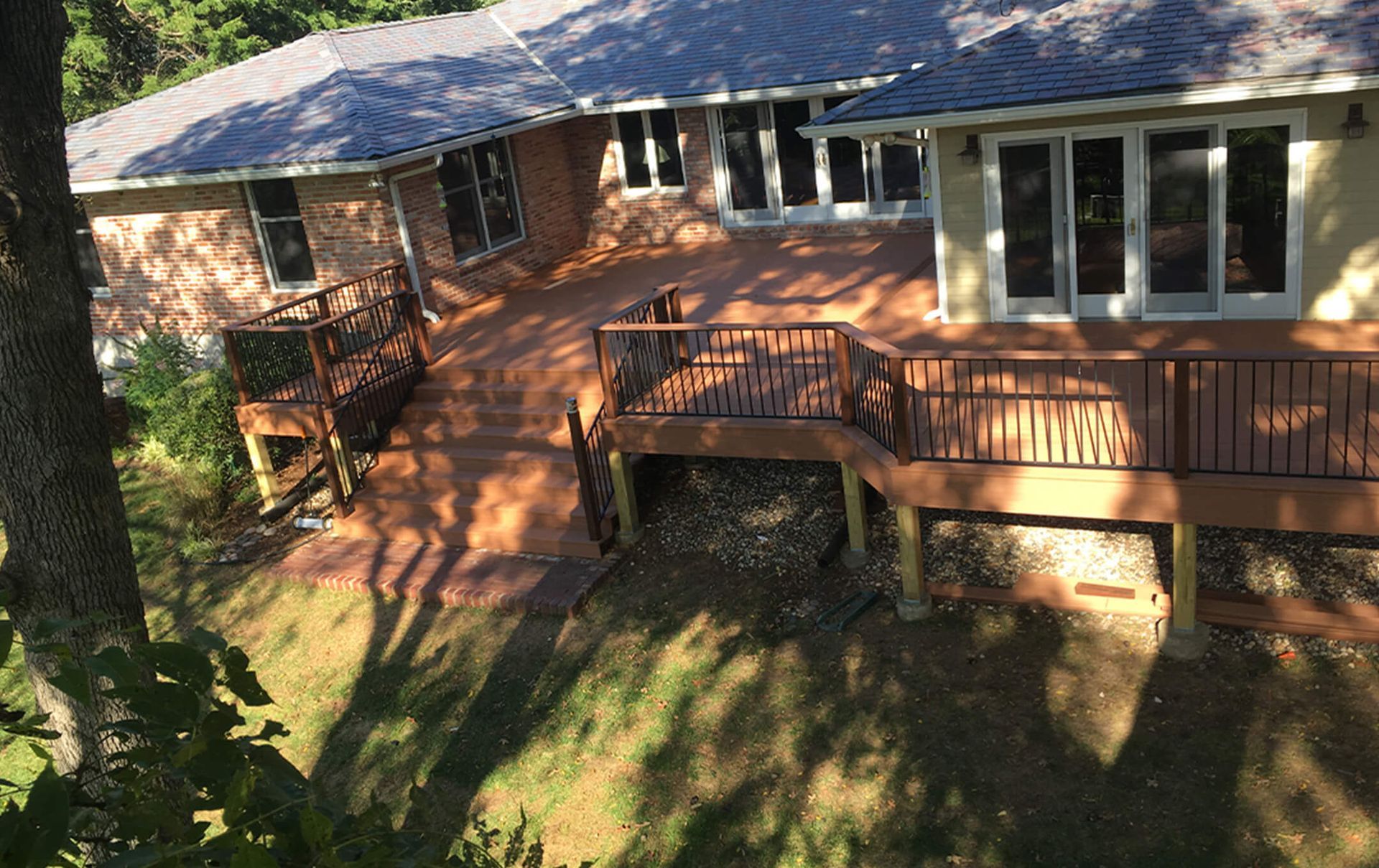 An aerial view of a house with a large deck surrounded by trees.
