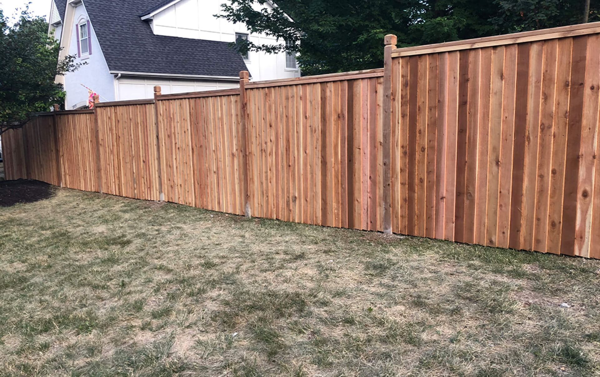 A wooden fence is in the backyard of a house.