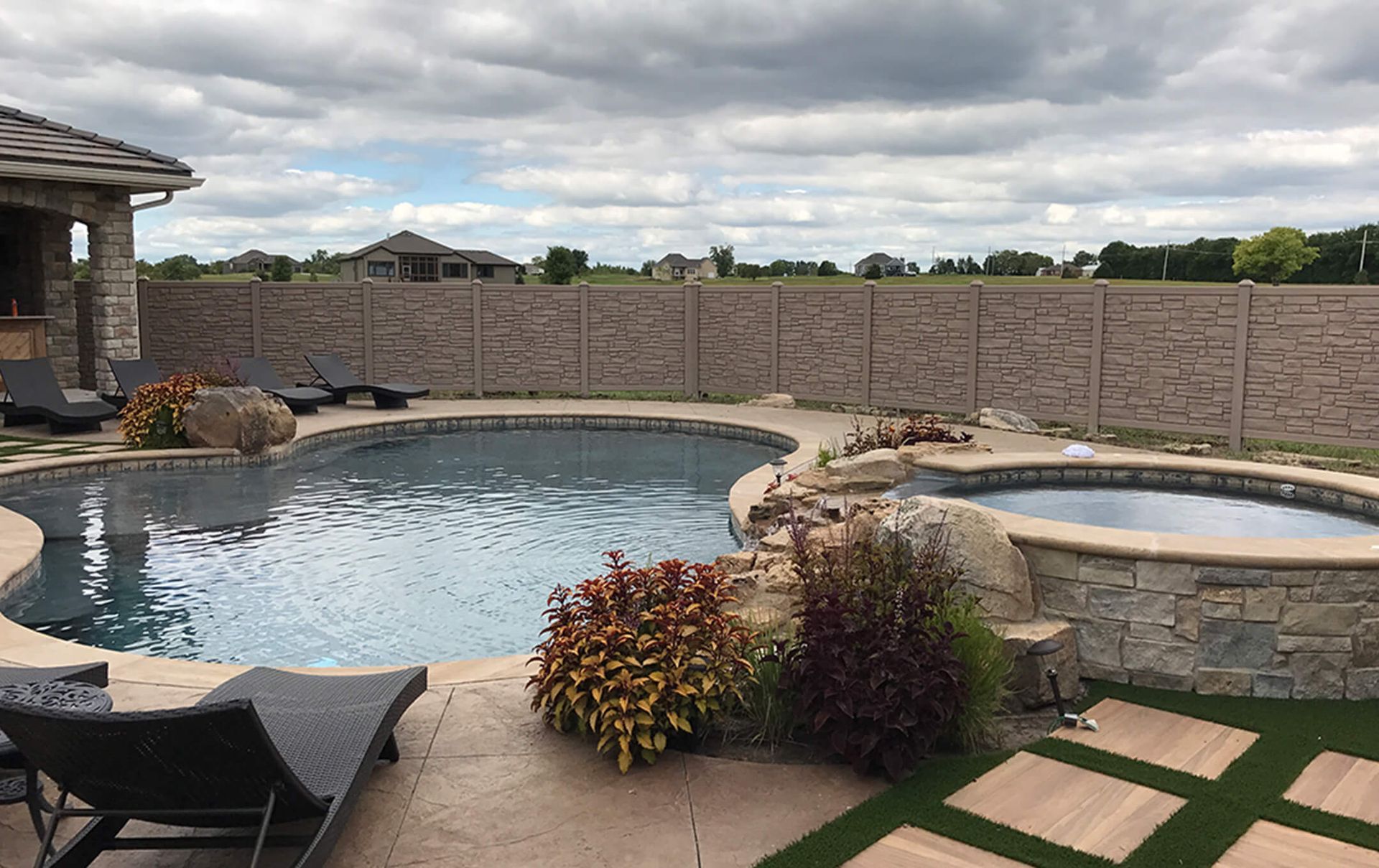 A large swimming pool with a hot tub in the backyard of a house.