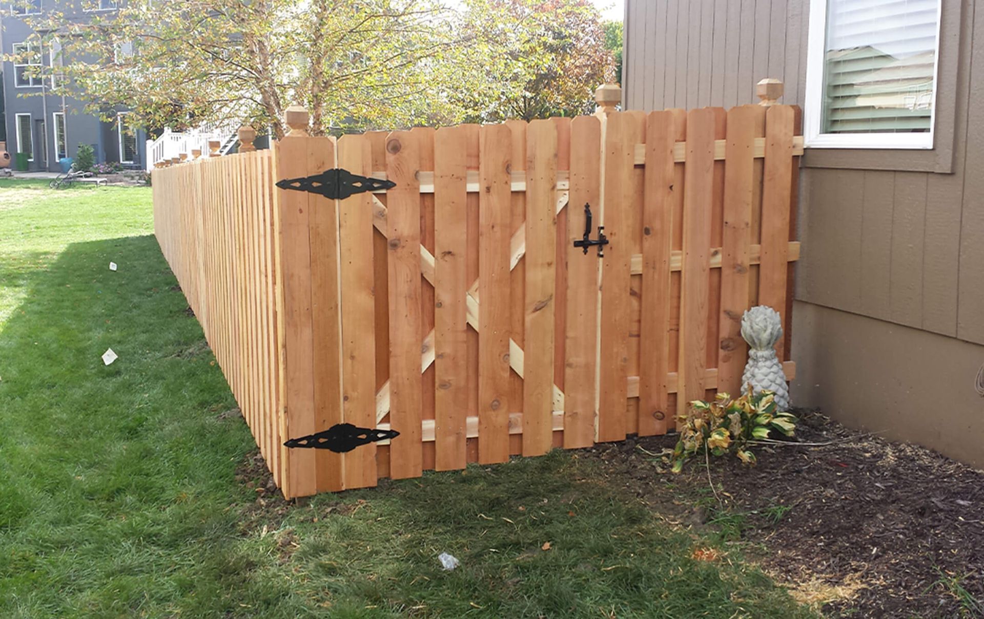 A wooden fence with a gate in front of a house.