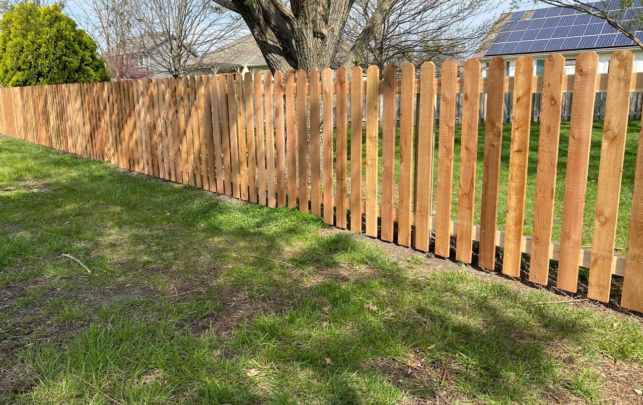A wooden fence is sitting in the middle of a lush green field.