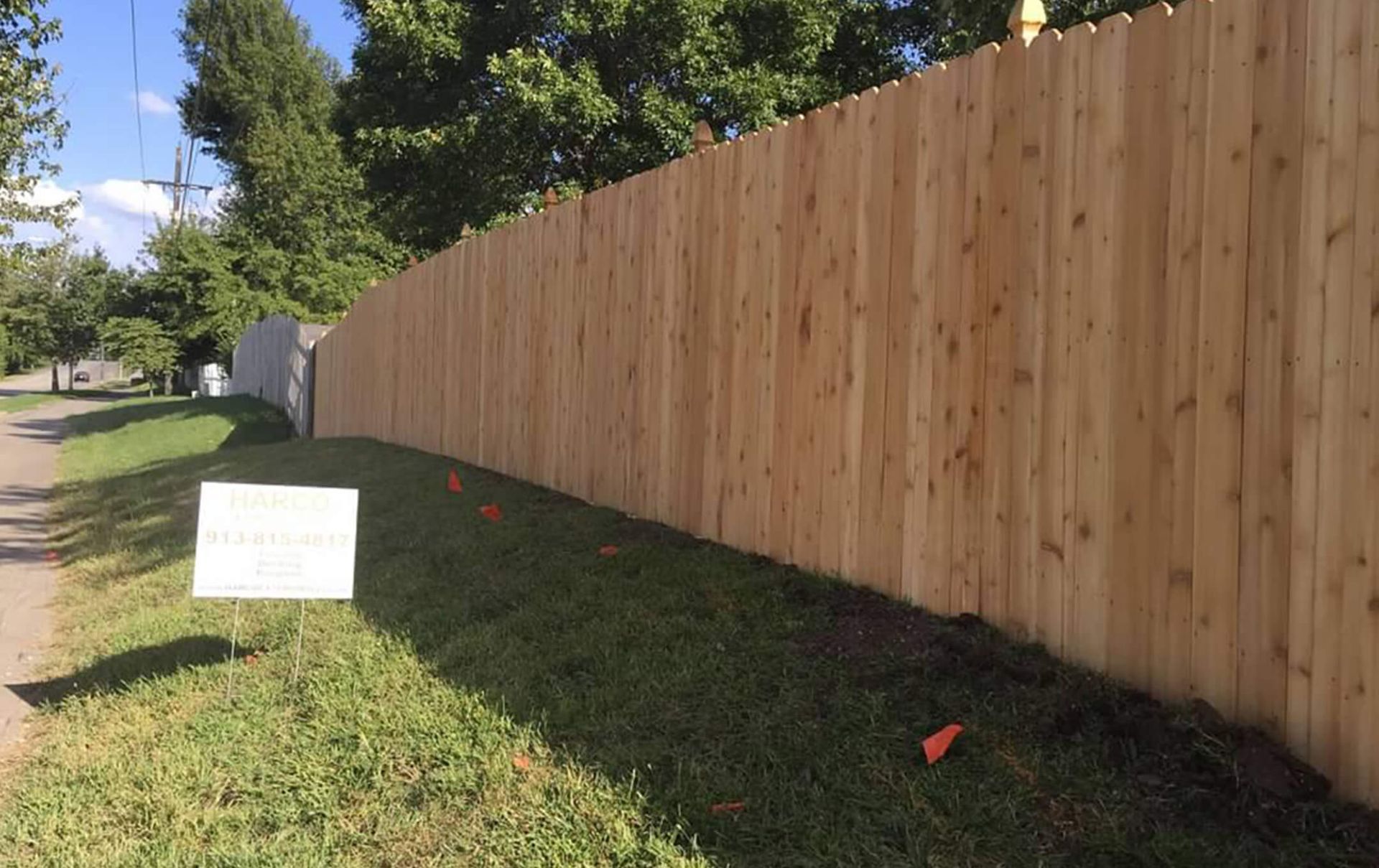A wooden fence with a sign in the grass next to it.