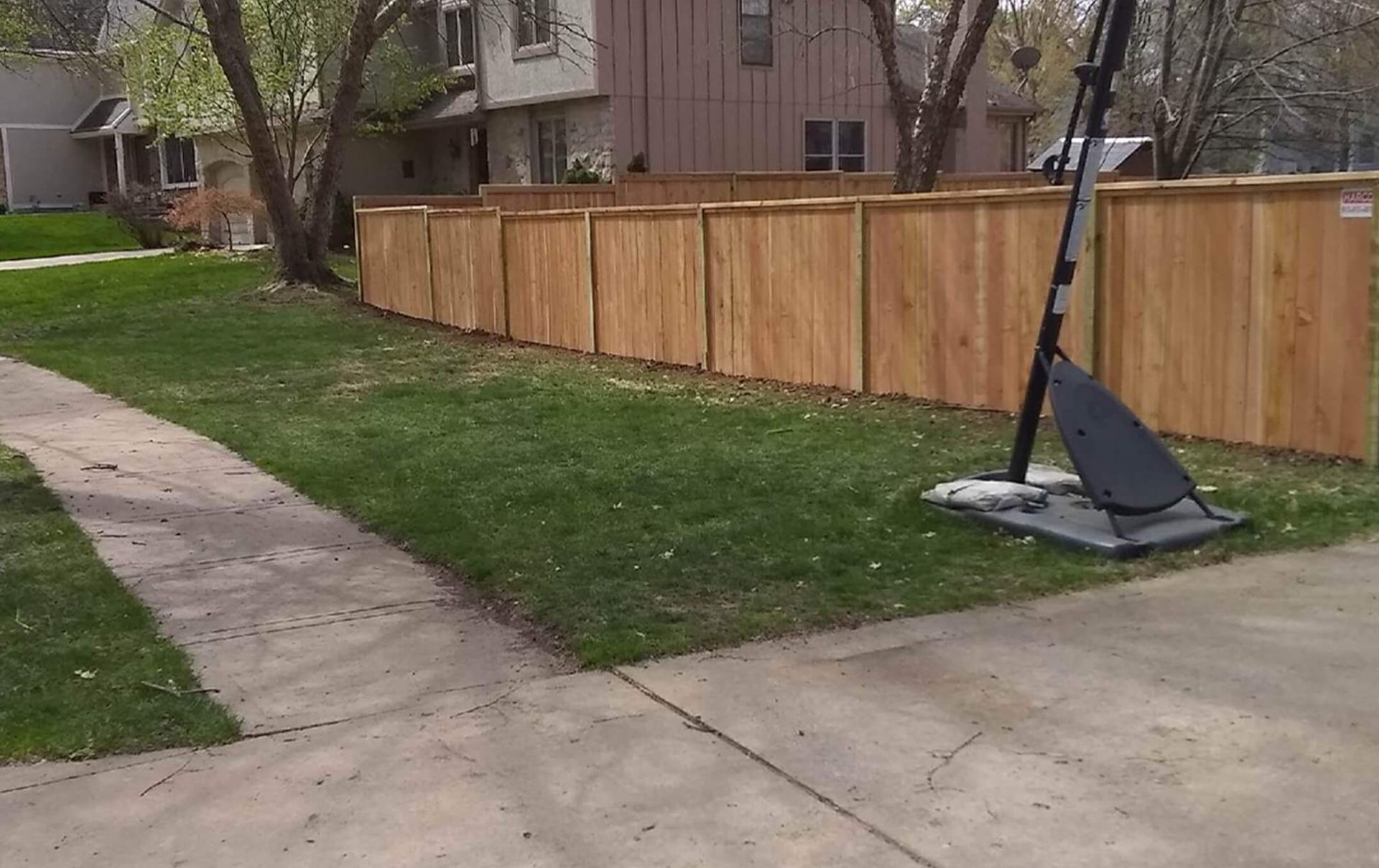 A wooden fence with a basketball hoop in front of it.
