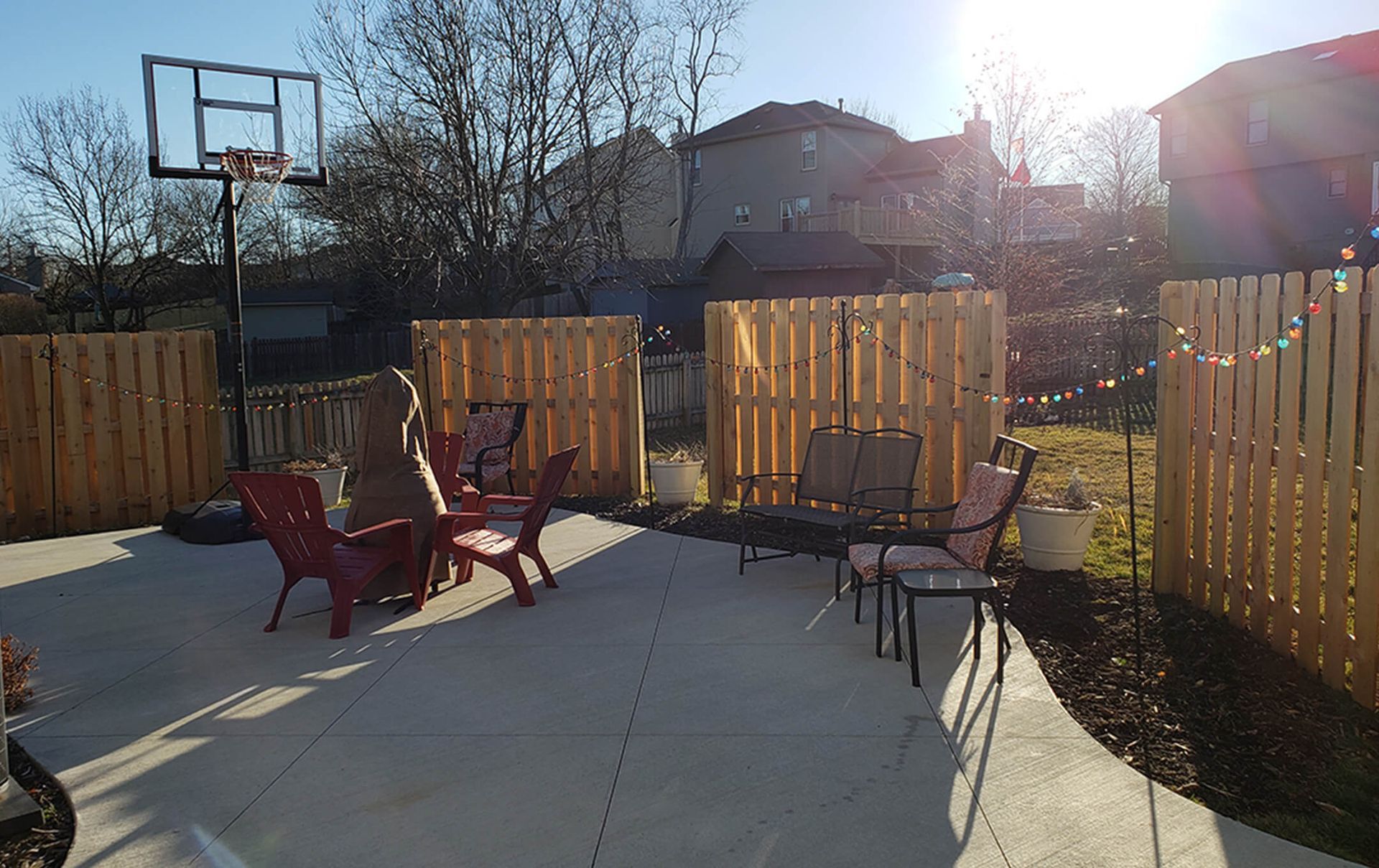 A patio with chairs and a basketball hoop in the backyard.