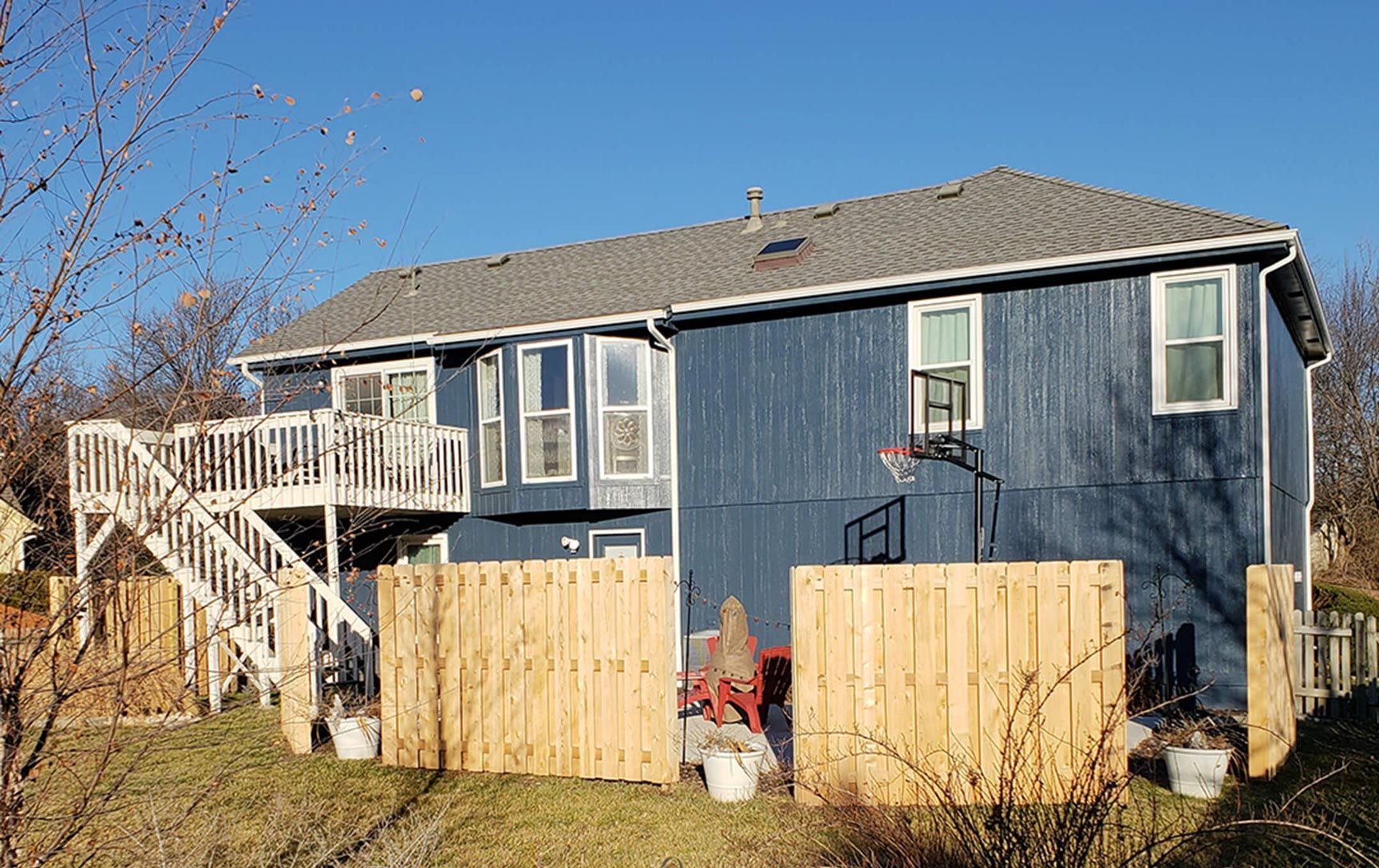 A blue house with a wooden fence and a deck.