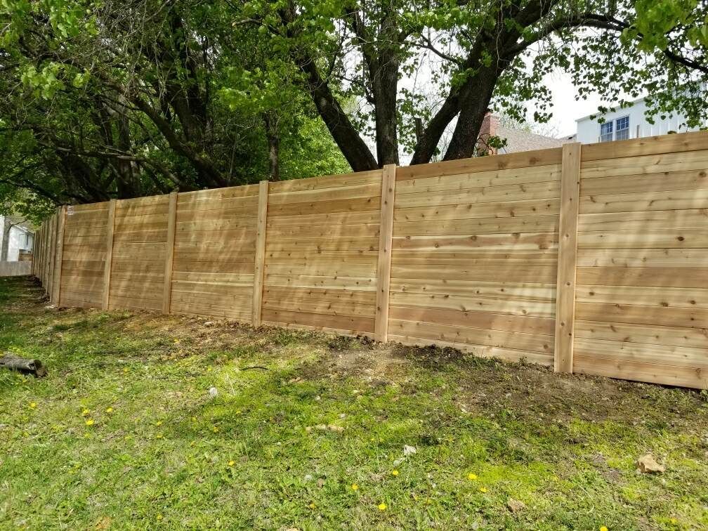 A wooden fence is sitting in the middle of a lush green field.
