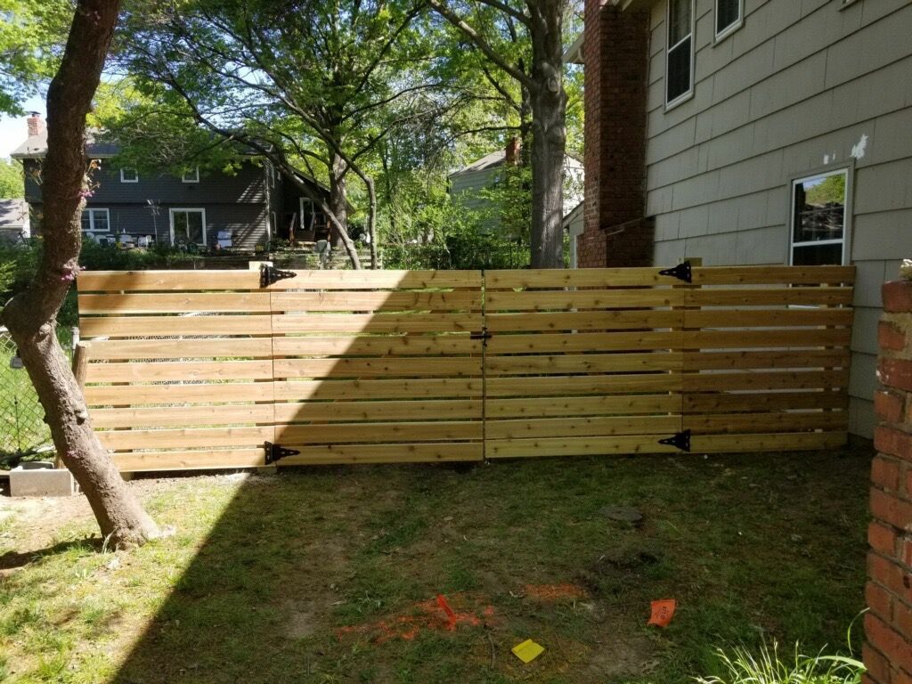 A wooden fence surrounds a backyard with a fire pit in the middle of it.