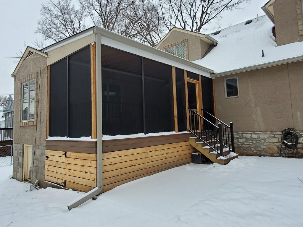 Screened-in porch attached to a house; snow-covered ground; wood and black screen construction.
