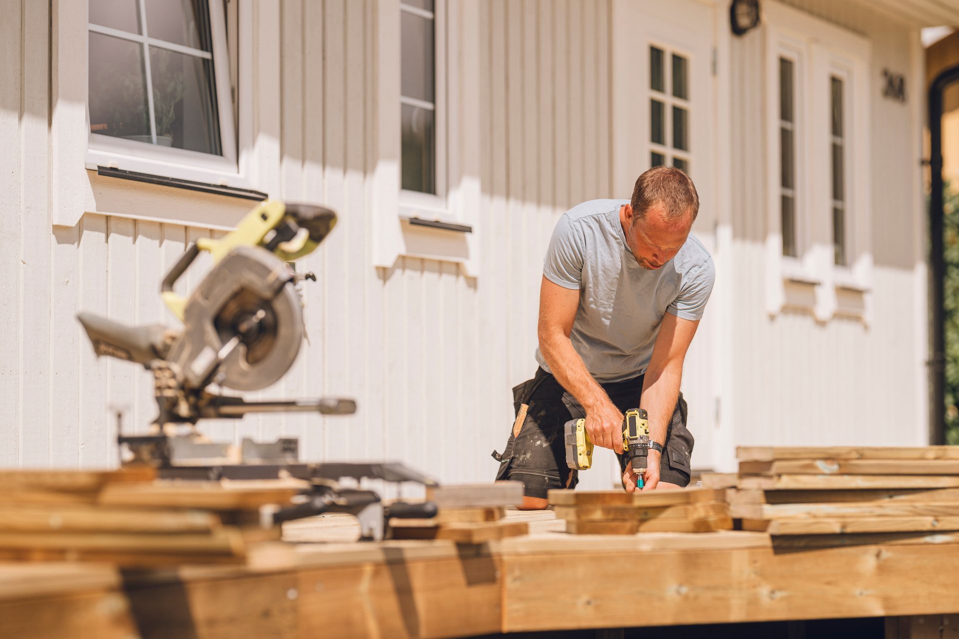 A man cuts decking lumber with a circular saw, showcasing skill as a residential deck builder.