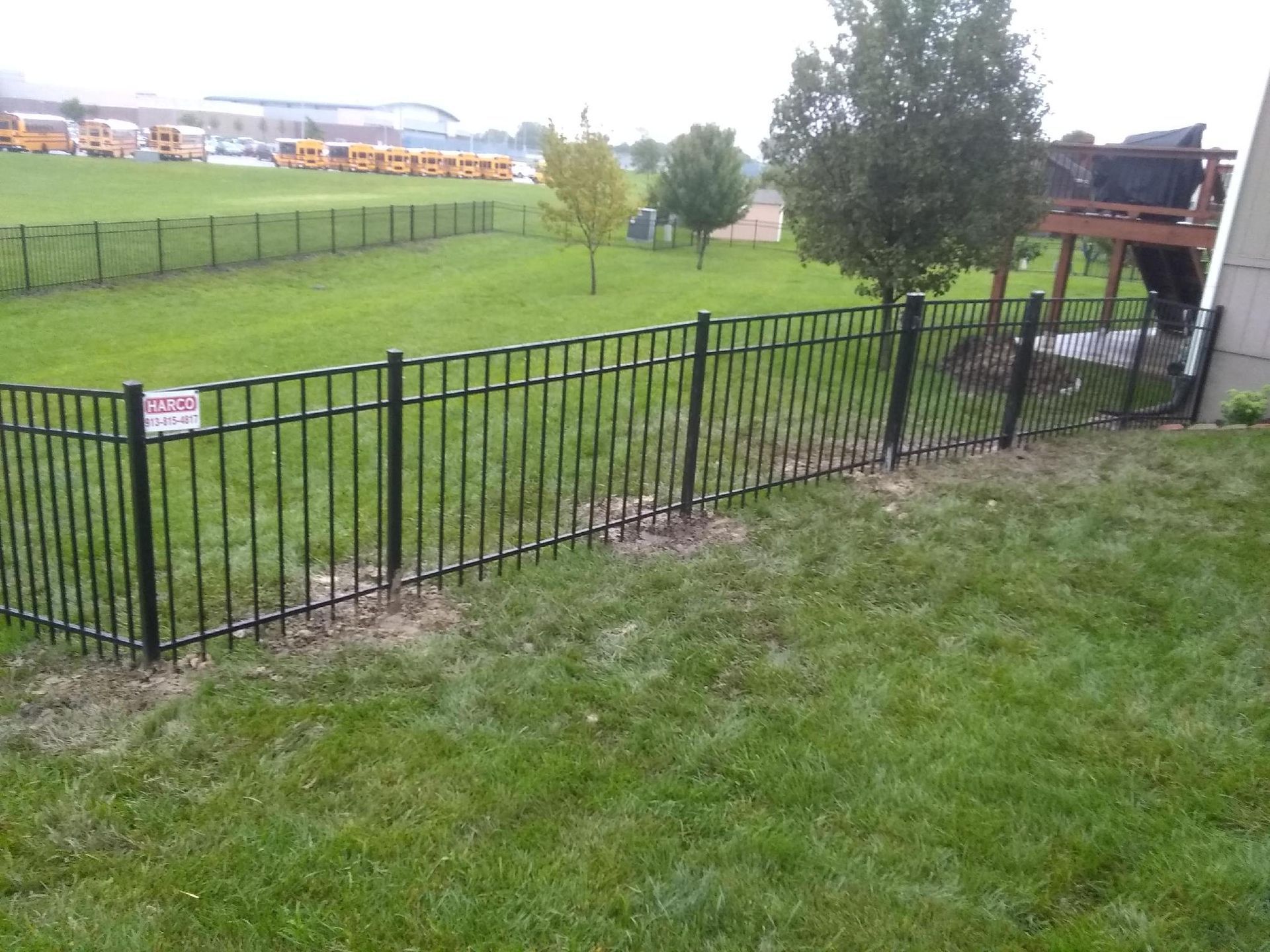 A black metal fence surrounds a lush green field.