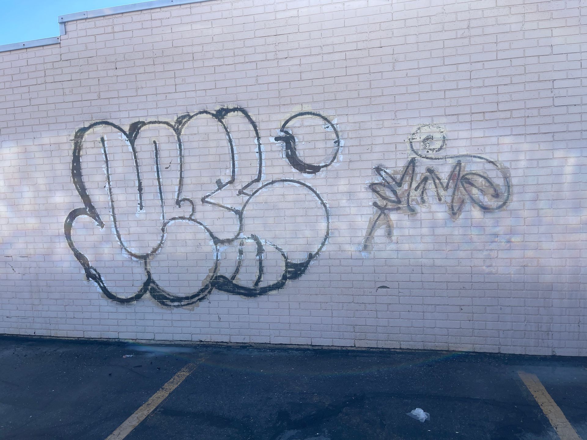 Graffiti on a white brick wall with blue outlined lettering and a small starburst tag beside it