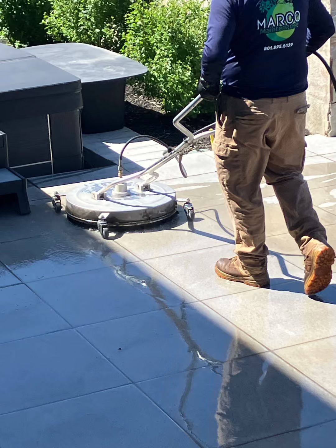 Worker cleaning a rooftop with a circular pressure washer attachment