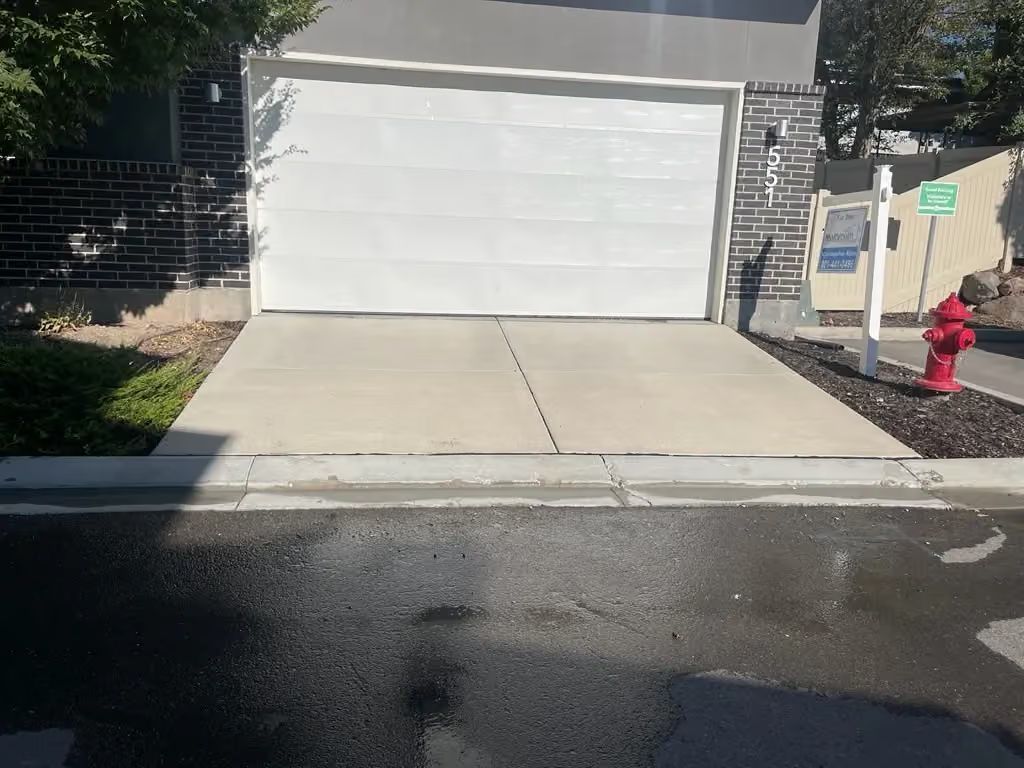 Driveway leading to a white garage door, with a red fire hydrant on the right side.