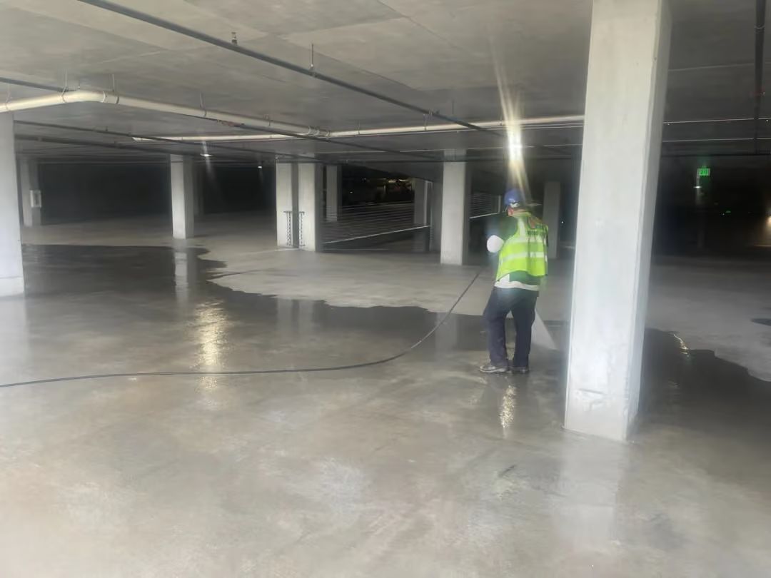 Worker in a high-visibility vest standing in a concrete parking garage under construction