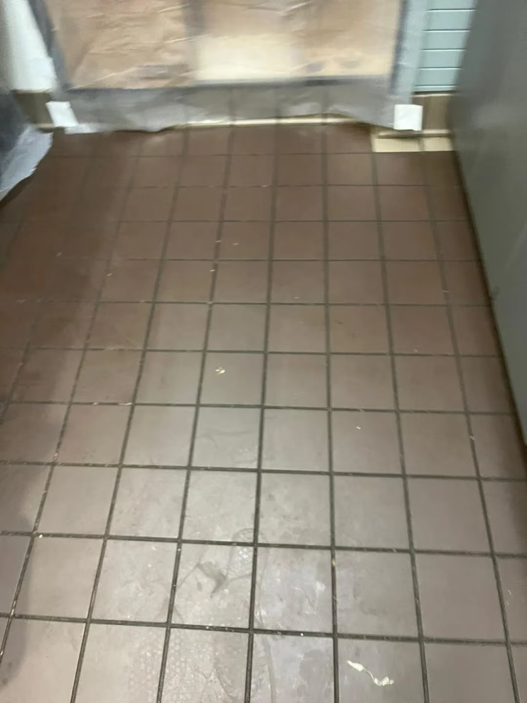 Tiled floor in a narrow hallway or entryway, with a plastic barrier at the far end.