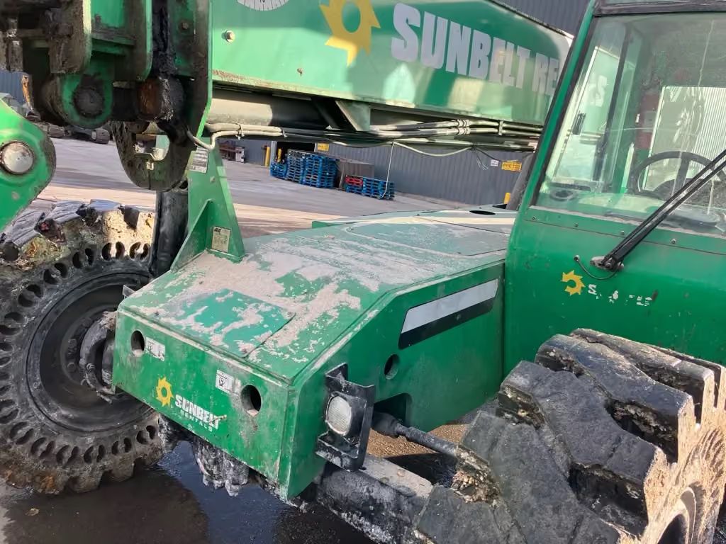 Green Sunbelt construction machine with muddy tires parked outdoors