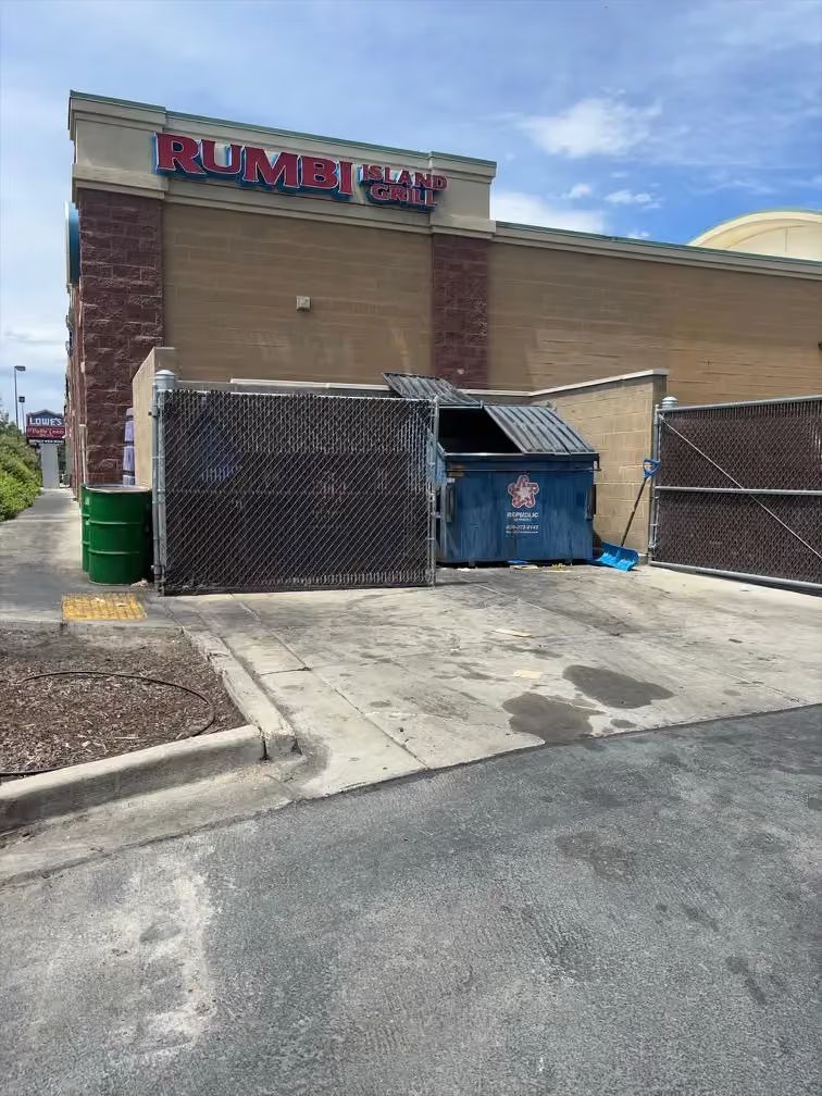 Rumba restaurant exterior with dumpster enclosure and cracked parking lot