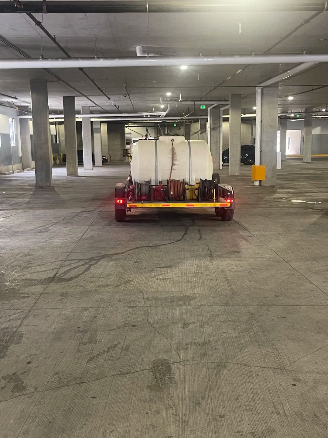 Small utility cart with white tanks parked in an empty concrete parking garage