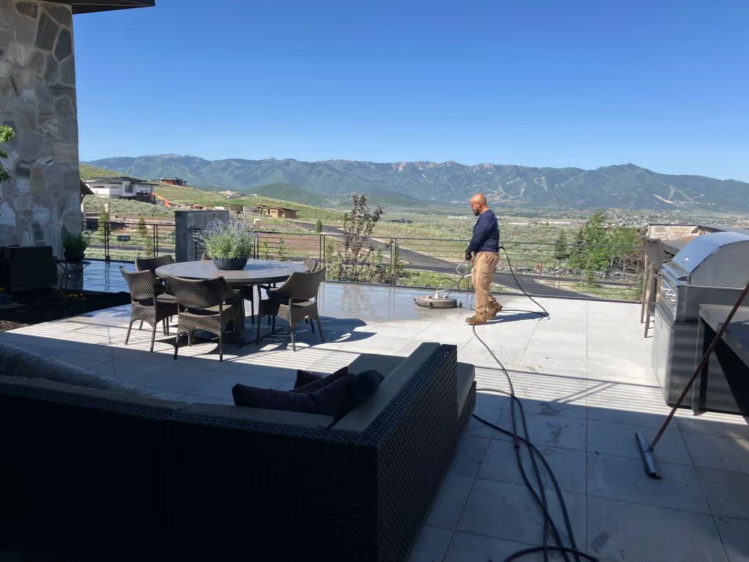 Patio with outdoor dining set and grill overlooking mountains under a clear blue sky