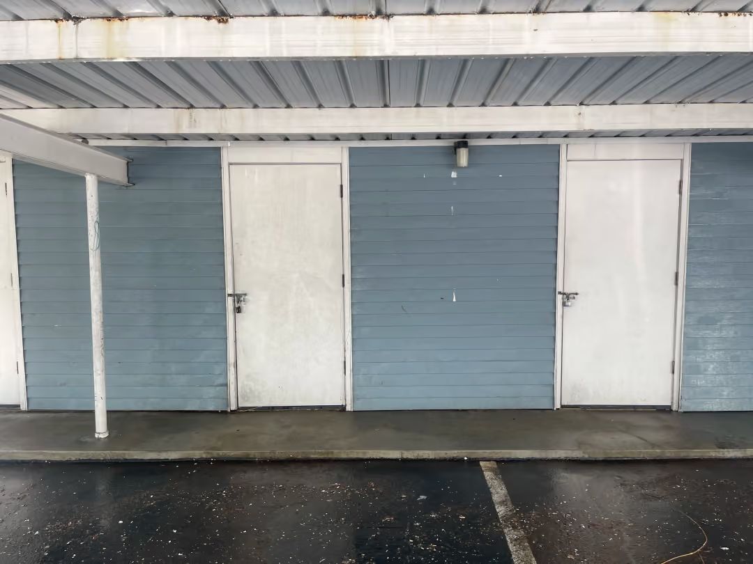 Blue and white storage unit doors under a covered parking area