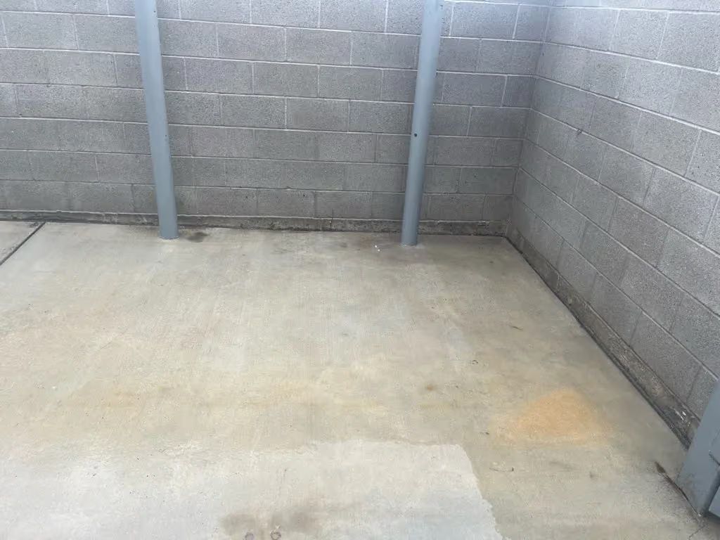 Empty concrete storage area with cinderblock walls and metal support posts.