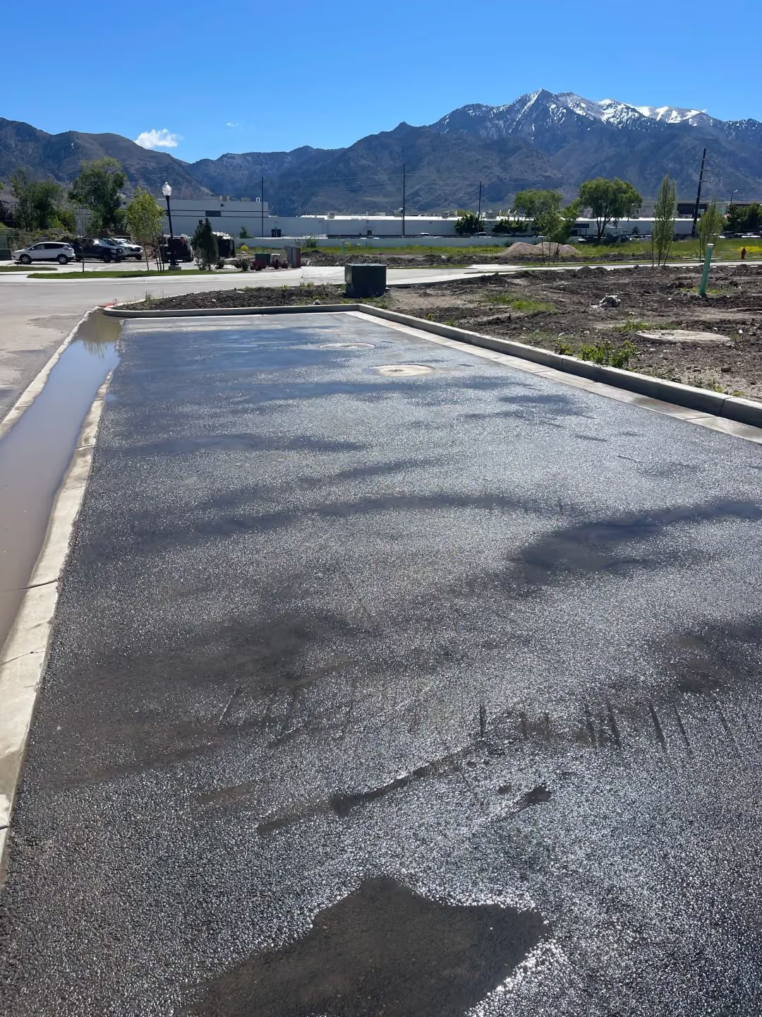 Paved road beside a canal with mountains and blue sky in the background