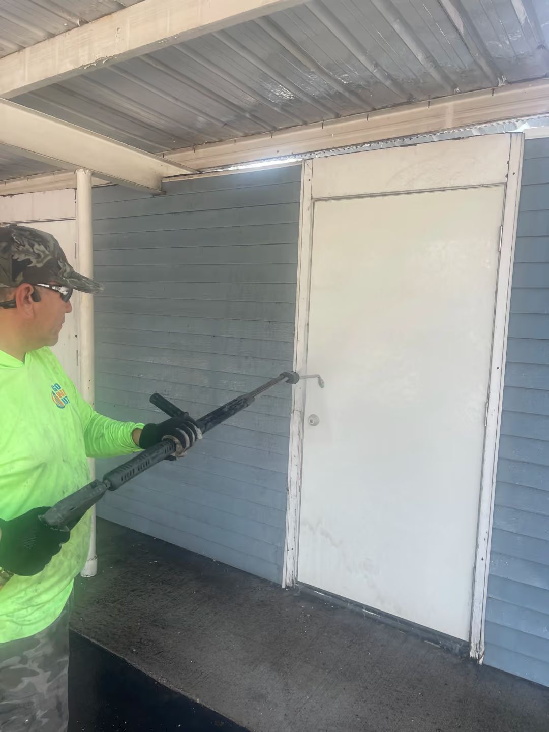 Person in neon shirt using a crowbar to pry open a white door on a blue building porch