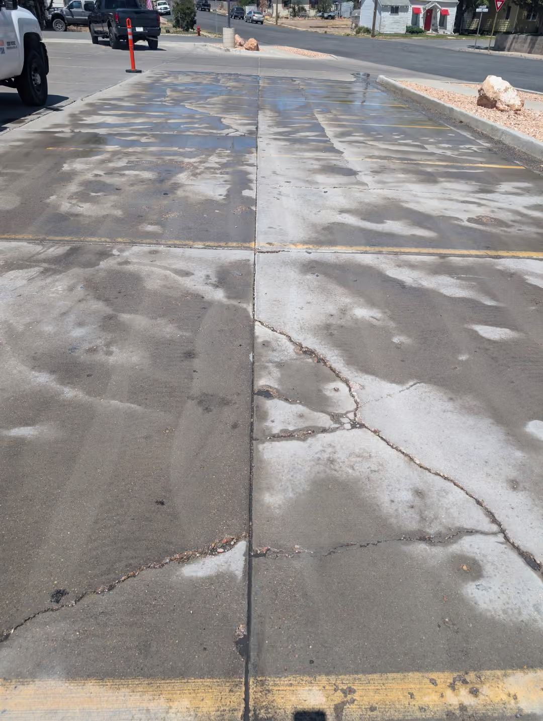 Cracked, patchy sidewalk with faded paint and a street view ahead