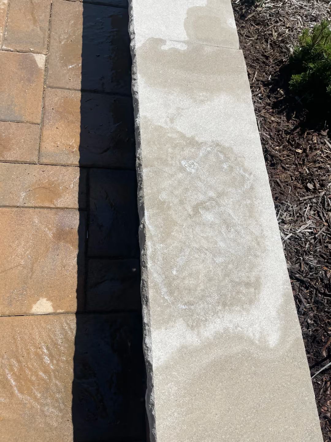Stone pavers beside a light concrete curb with a narrow shadowed gap between them