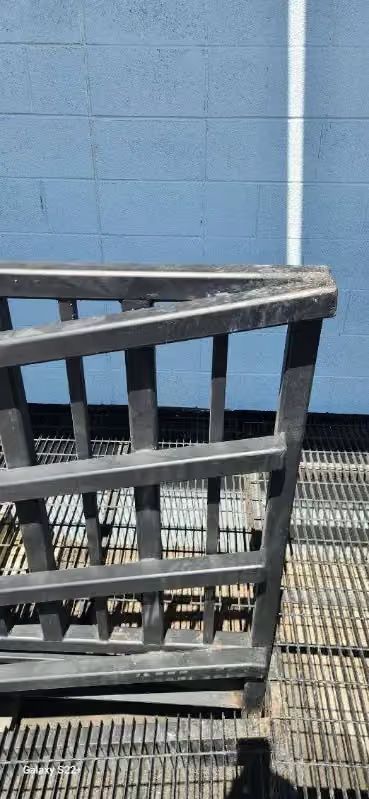 Black metal chair on a grated floor beside a blue wall with a white stripe