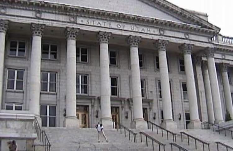 Wide stone steps lead to a neoclassical building with tall columns and a few people walking nearby