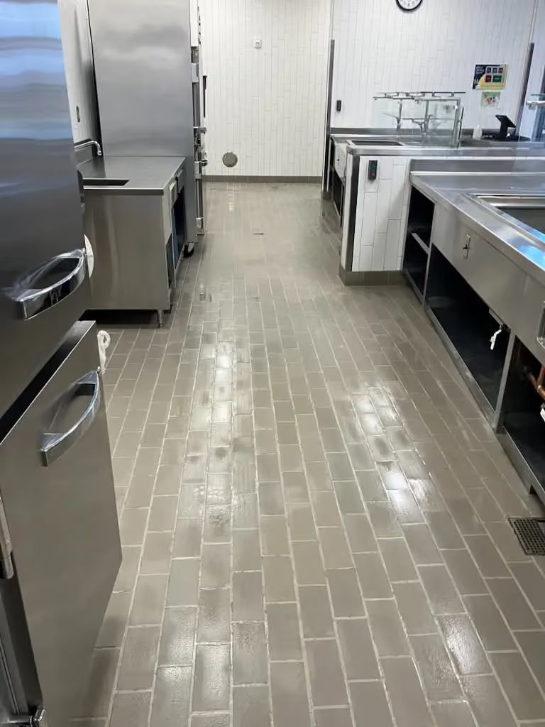 Commercial kitchen aisle with stainless steel appliances and counters along tiled floor