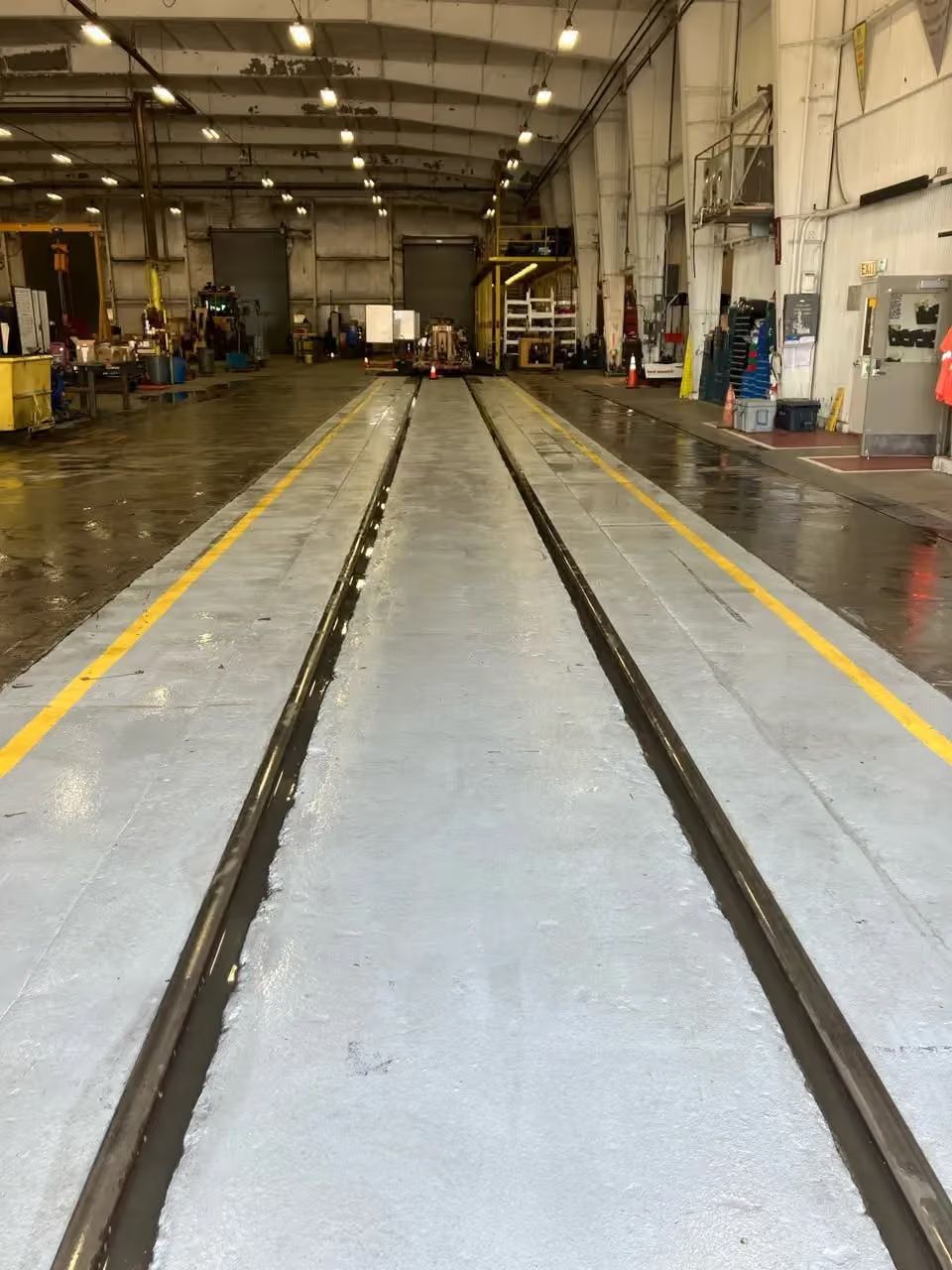 Industrial warehouse floor with long parallel tracks and yellow safety lines