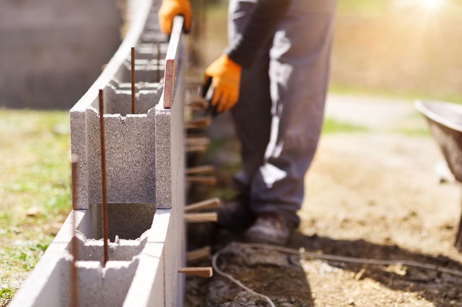 A man is laying concrete blocks on a sidewalk.