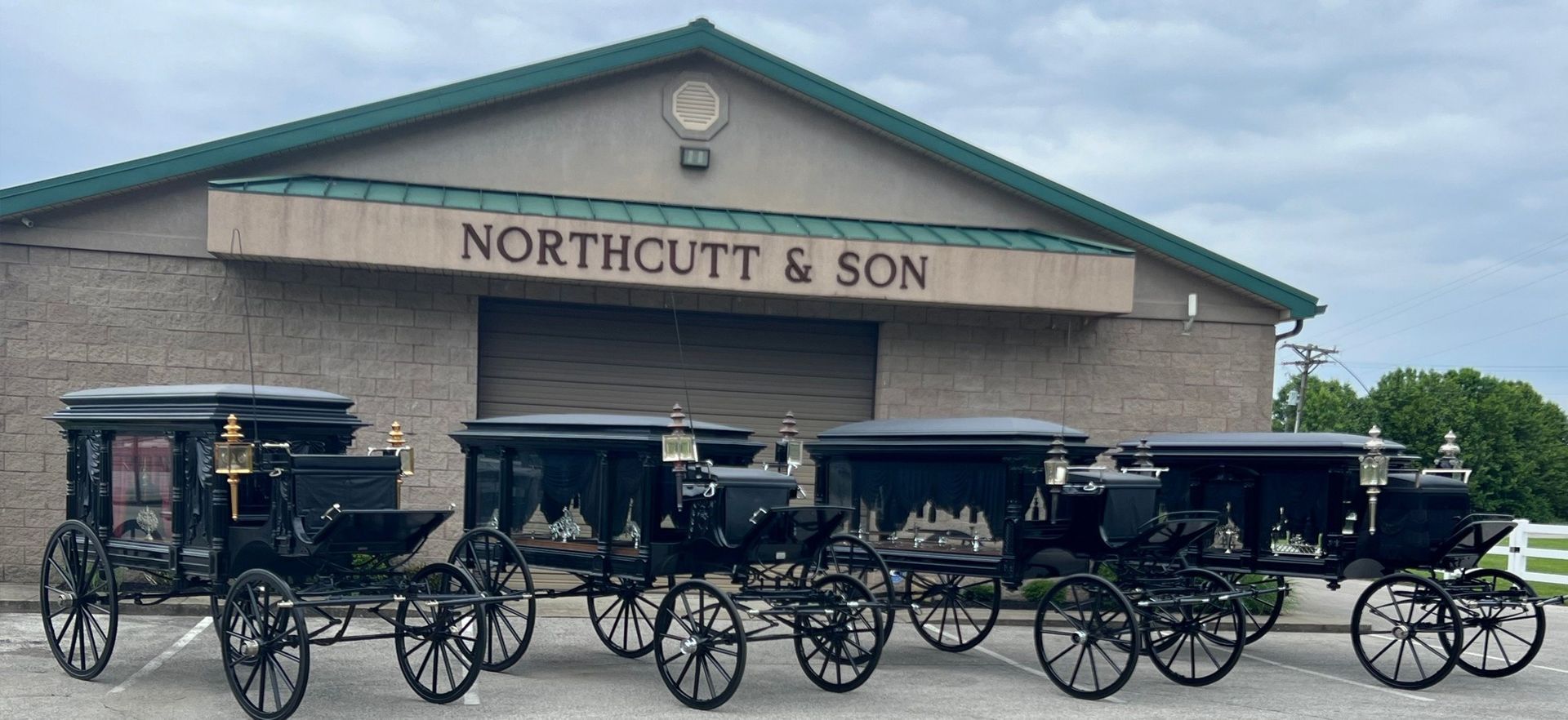 A row of horse drawn carriages are parked in front of a building.